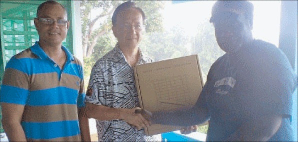 Pictured is Trade Commissioner Daniel Hu presenting the solar kits to Mr Beani, while North Bougainville MP Lauta Atoi looks on.